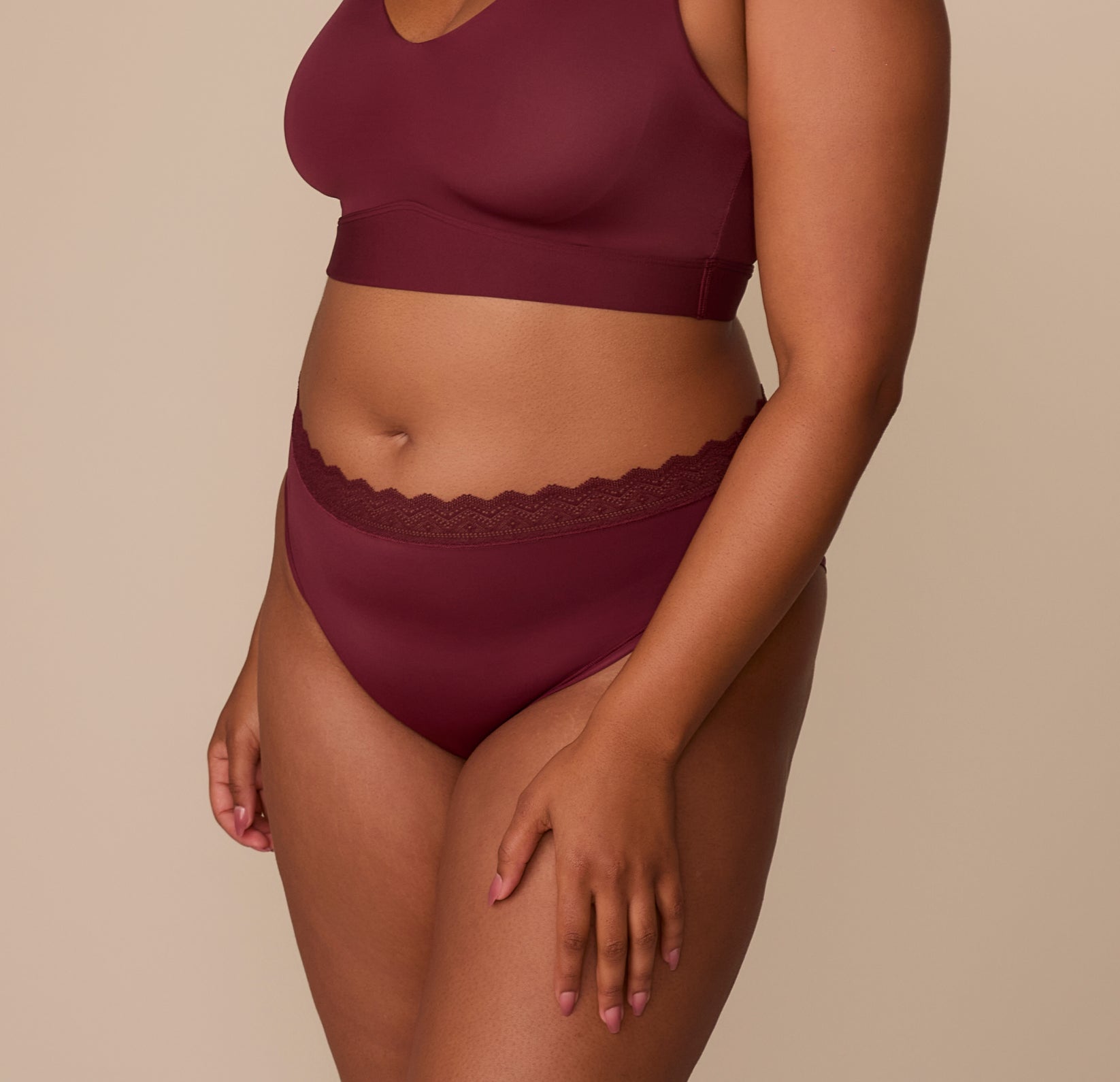 Side angle of Zarria wearing the Bliss Lace Highwaist Brief in Bordeaux, highlighting the clean leg openings and gently sculpted shape.