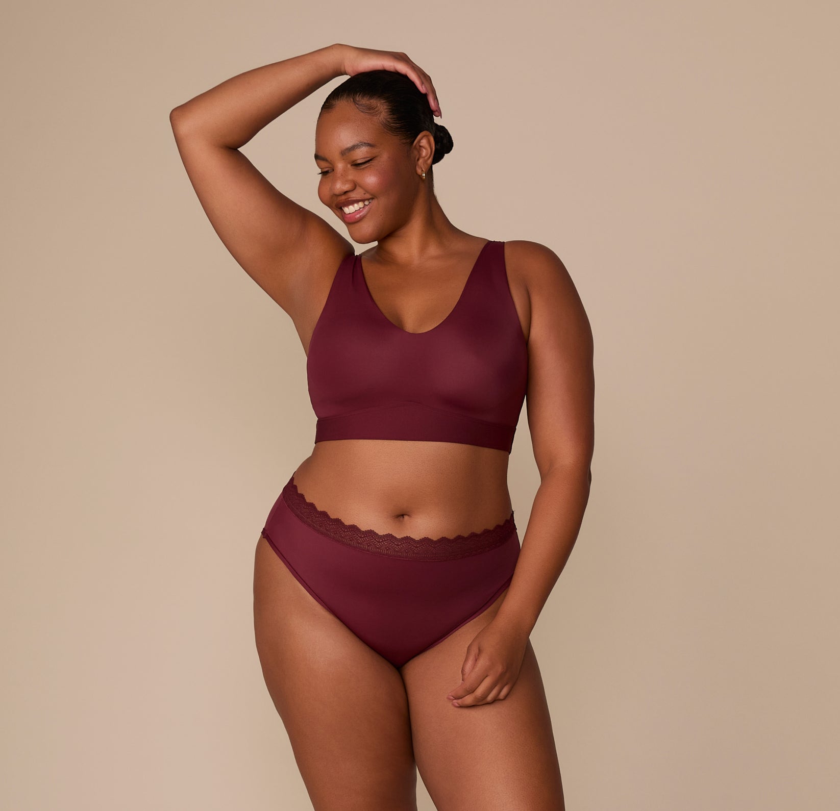 Zarria smiles while wearing the Bliss Lace Highwaist Brief and matching Bliss Bralette in Bordeaux. The set features a high-rise waist and ultra-soft materials designed for everyday comfort.