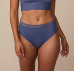 Close-up front view of Nemesis wearing the Bliss Lace Highwaist Brief in Twilight. The image highlights the soft, high-rise waistband with scalloped lace trim and the smooth, seamless finish over the hips. sizing: Nemesis wears size Medium