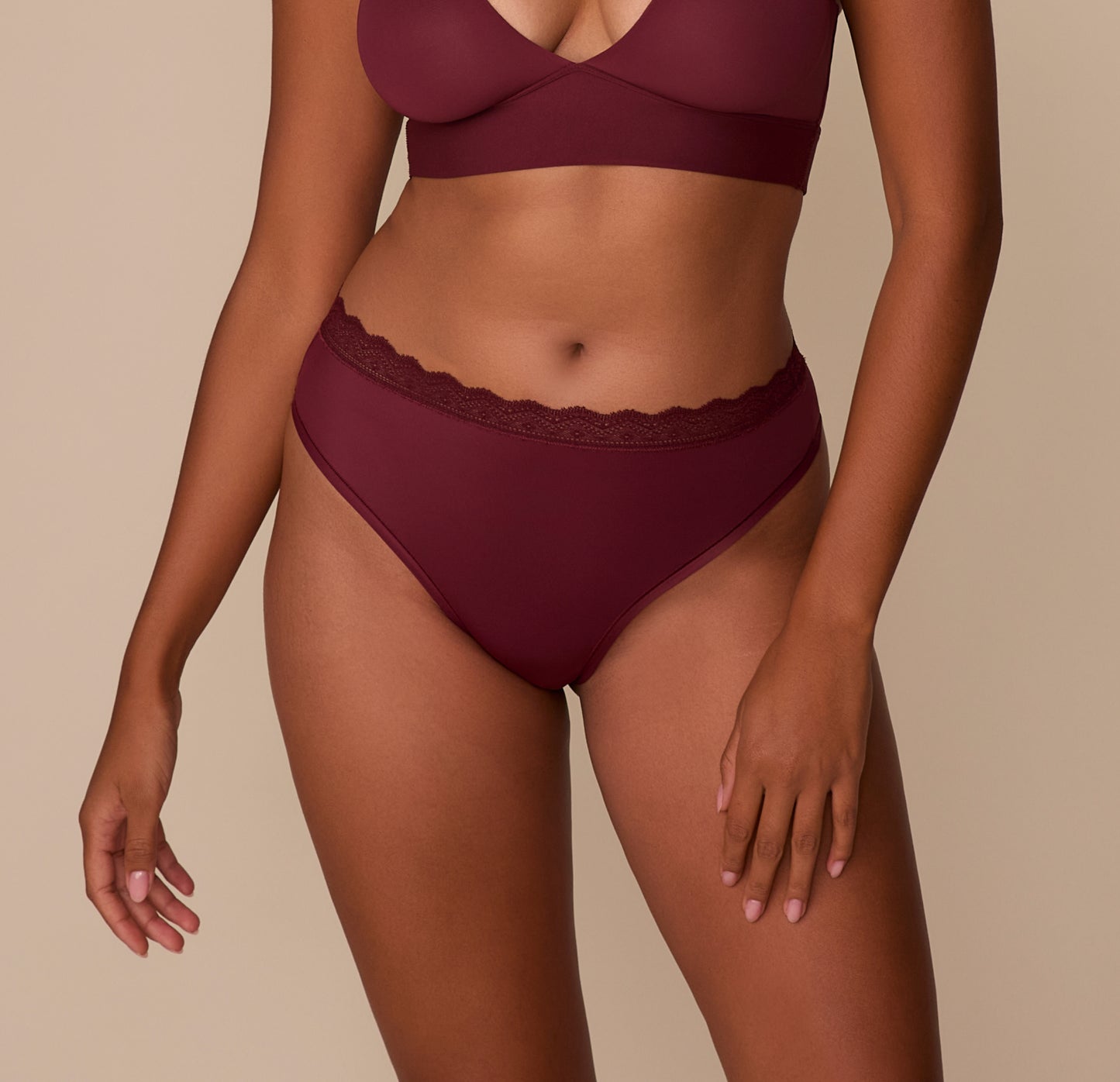 Model Victoria wears the Bliss Lace Highwaist Thong in Bordeaux. The front view highlights the ultra-soft microfiber fabric and lace-trimmed waistband designed to sit comfortably at the natural waist. sizing: Victoria wears size Medium