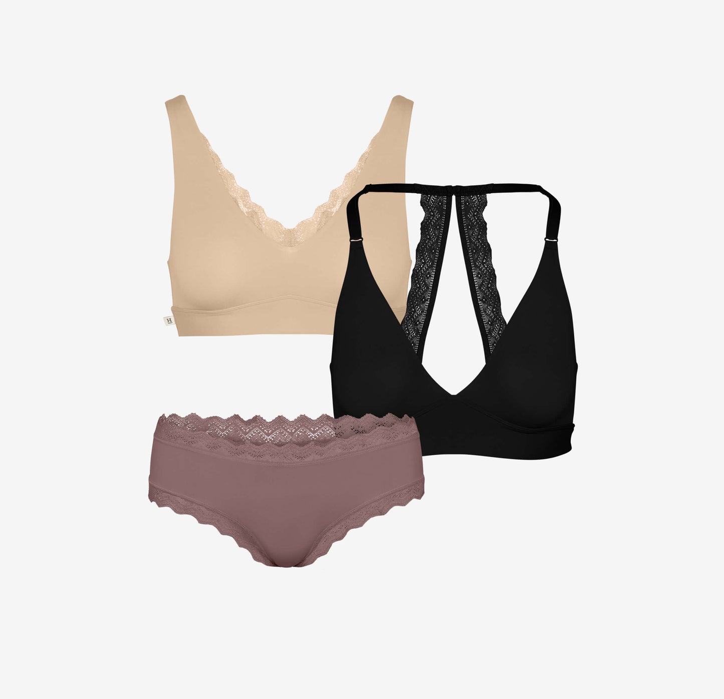 Product flat lay featuring Bliss Lace Bralette in beige, Bliss Lace Halterneck Bralette in black, and Bliss Lace Cheeky in mauve. All styles showcase delicate lace detailing.