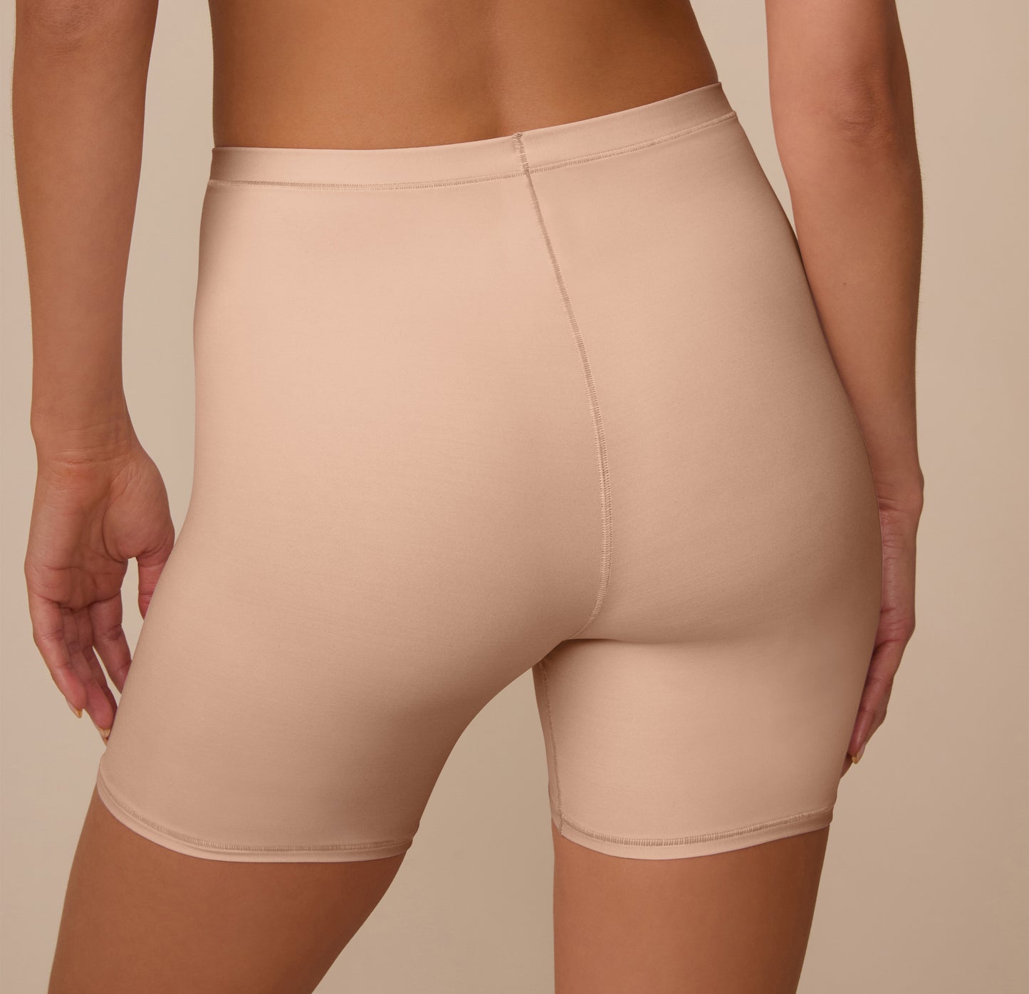 Back view of Marcela in the Bliss Under Short in Beige, showing the smooth microfiber fabric and natural shaping without digging or bunching.
