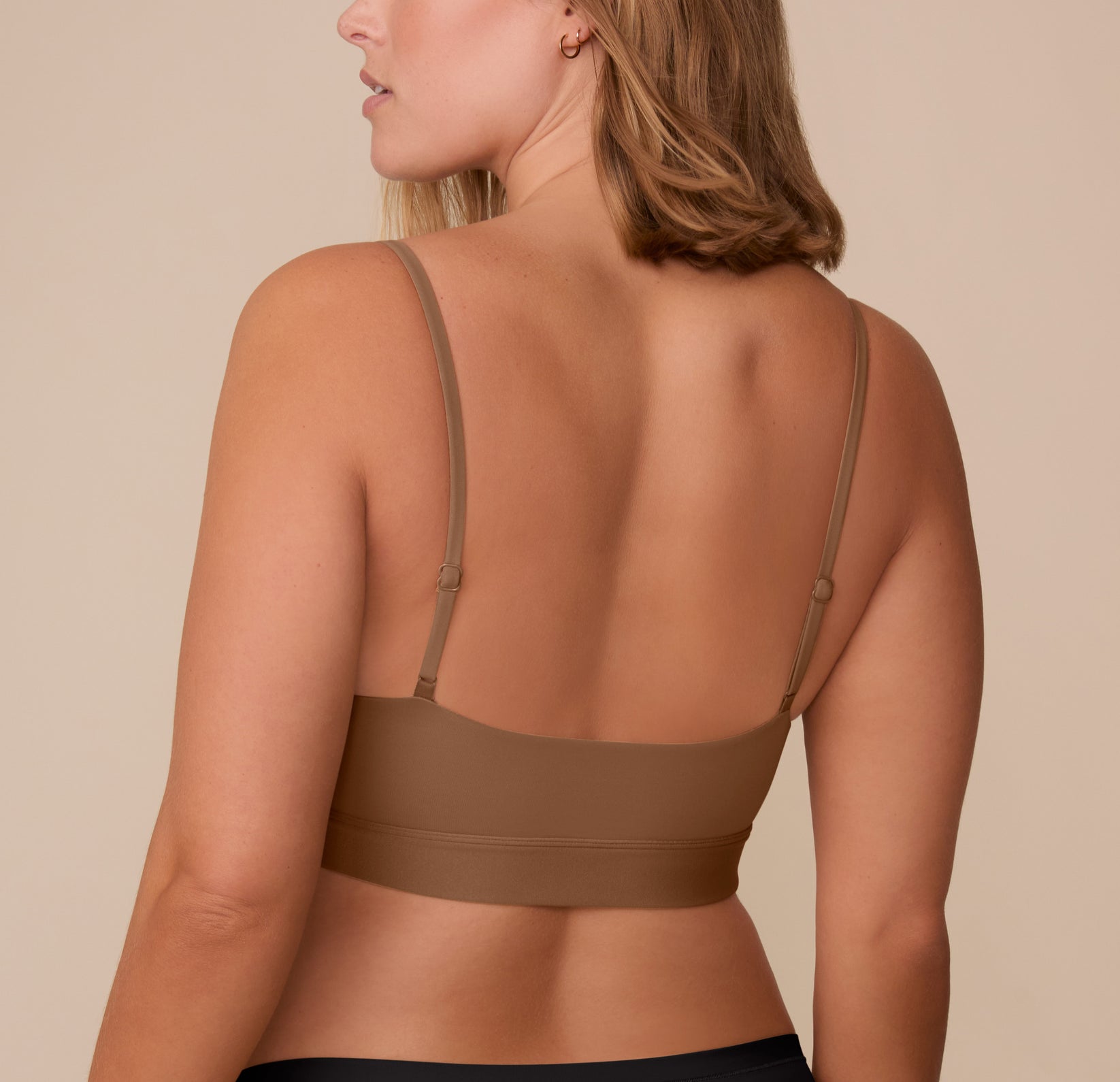 Back angle of Sonnie in the Bliss Scoop Bralette in Brown, highlighting the bralette's wide back band and adjustable straps.