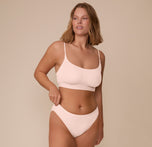 Full-body shot of Sonnie wearing the Bliss Scoop Bralette and matching Bliss Bikini in Rose. The image captures the soft, supportive fit of the tonal set.