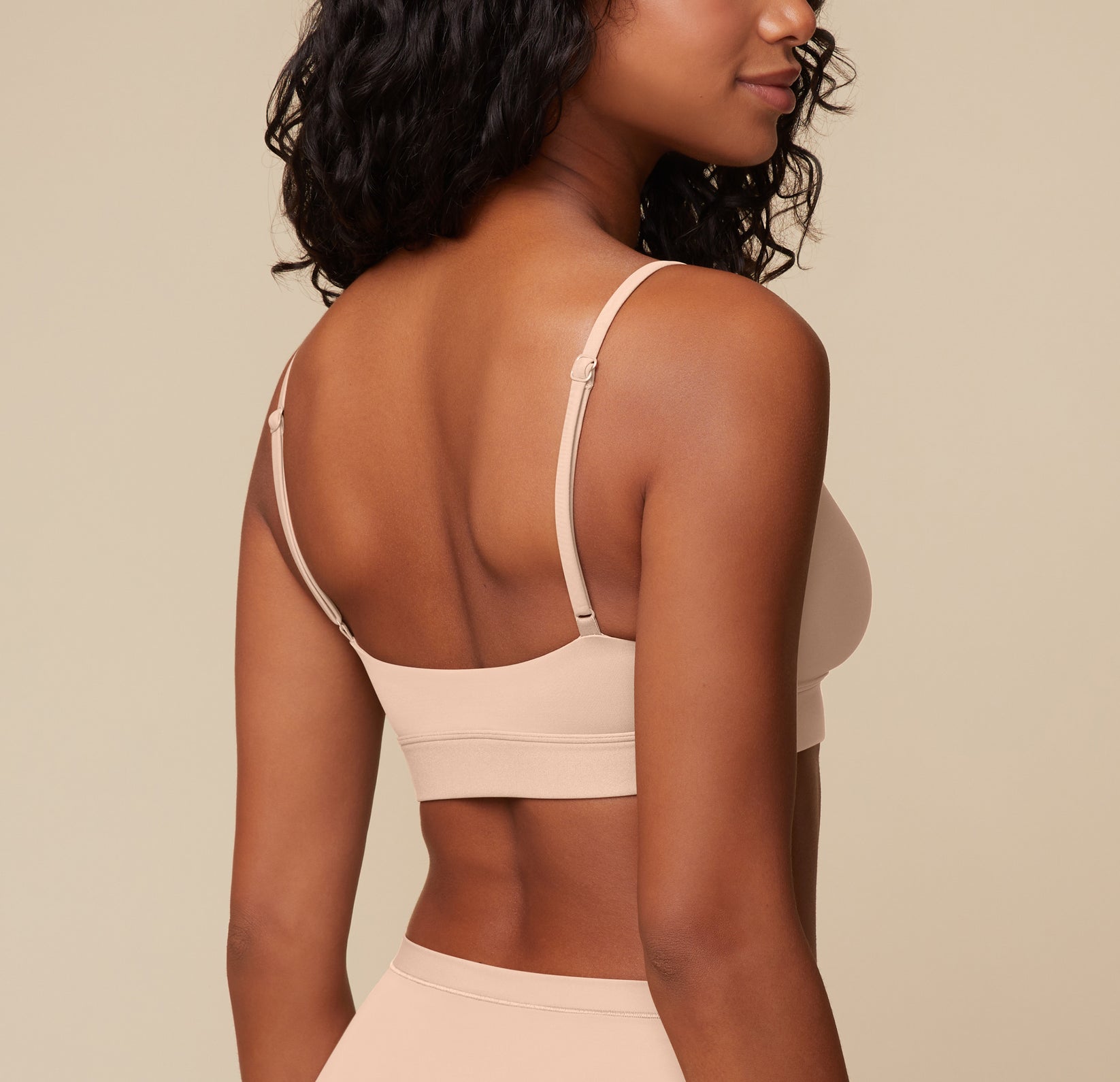 Rear view of Ally wearing the Bliss Scoop Bralette in Beige, showing the smooth, wireless back band and adjustable strap details.