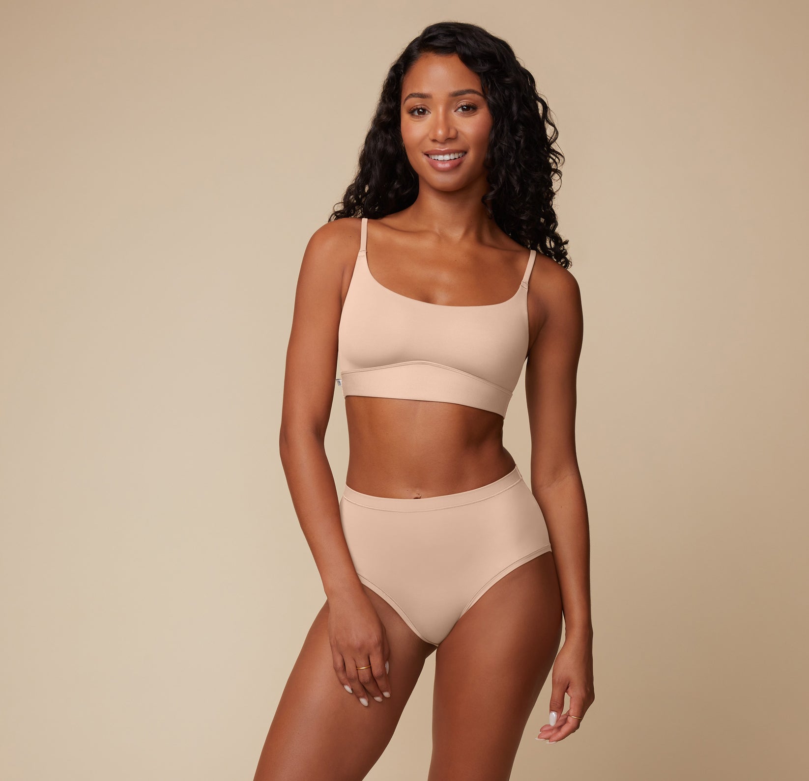 Full-body image of Ally wearing the Bliss Scoop Bralette and Bliss Highwaist Brief in Beige, standing against a neutral background.