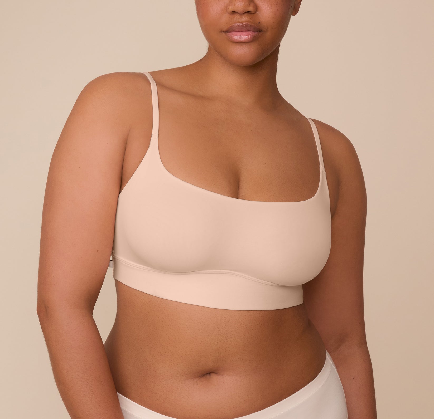 Zarria wearing the Bliss Scoop Bralette in Beige, shown from the front. The image highlights the wireless design and supportive scoop shape. sizing: Zarria wears size XL