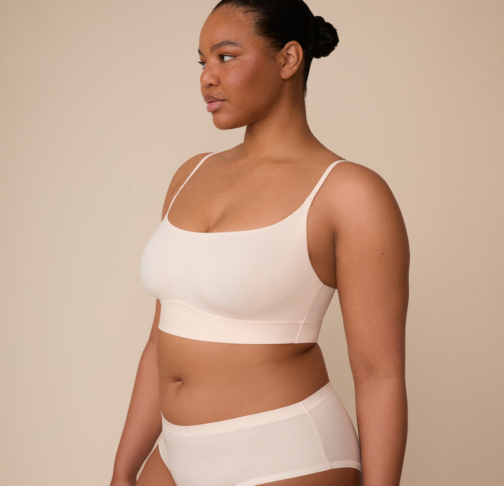 Three quarter profile of Zarria wearing the Bliss Scoop Bralette in Quartz. The image highlights the clean side seams and the sleek, minimal silhouette of the bralette.