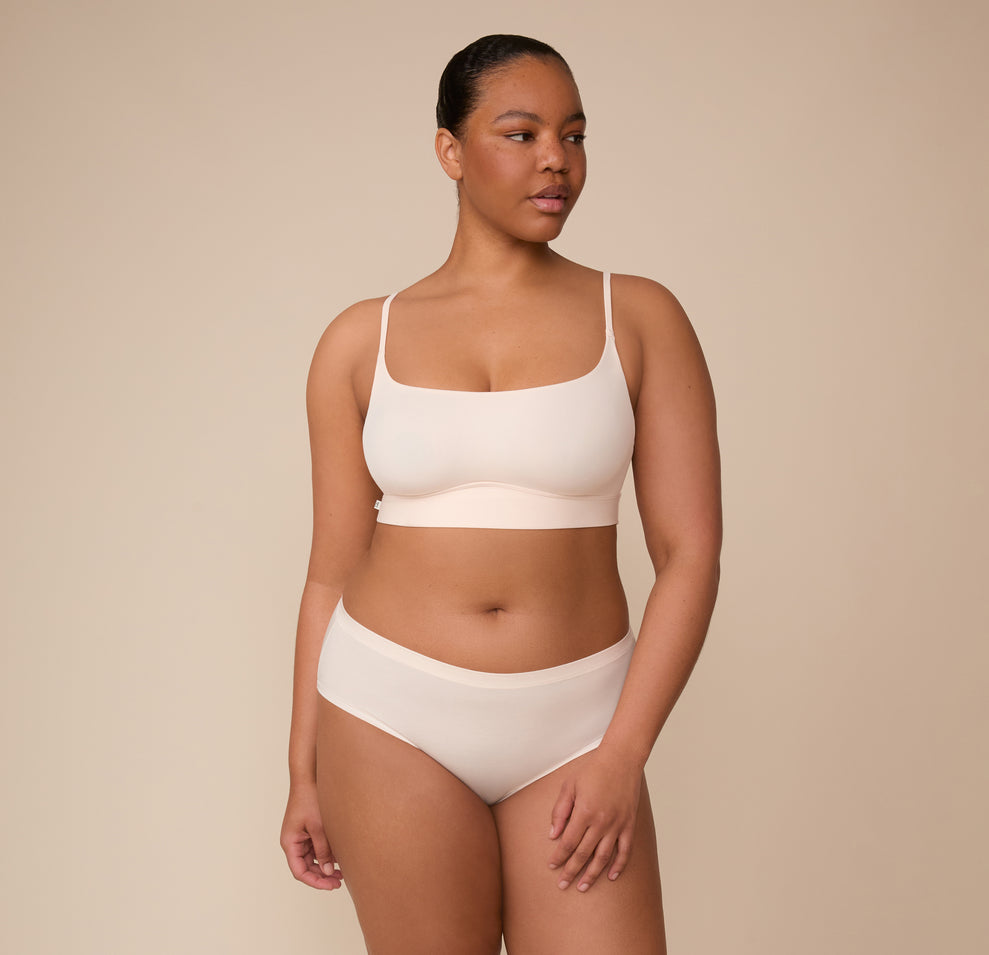 Zarria wears the Bliss Scoop Bralette with the Cloud Cotton Hiphugger Brief in Quartz. The full look emphasizes the set’s comfort-first design and flattering, barely-there feel.