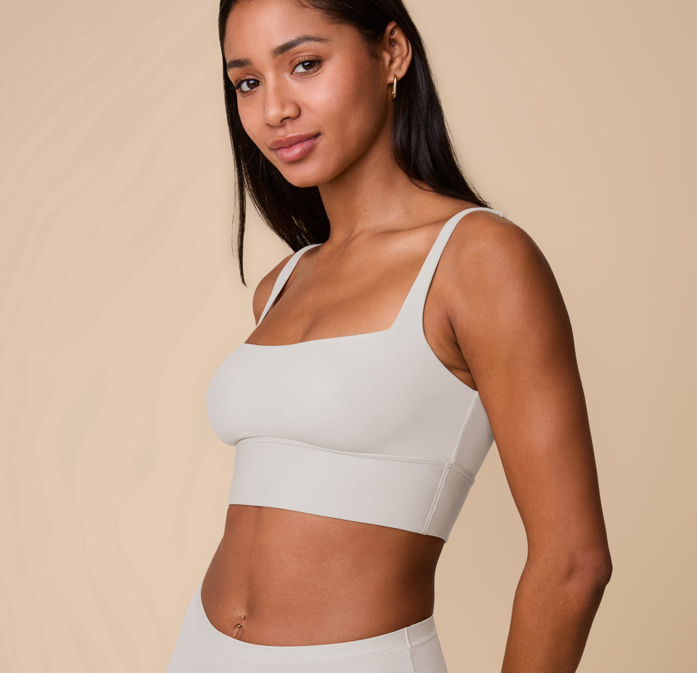 Three-quarter view of Ally in the Bliss Square Neck Bralette in Frost, smiling slightly. This angle emphasizes the sleek neckline and supportive structure of the bralette.
