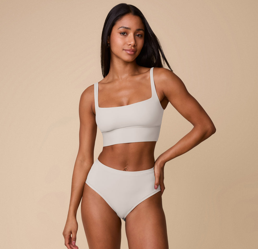 Full-body shot of Ally wearing the Bliss Square Neck Bralette and matching Highwaist Brief in Frost. The image captures the set’s minimalist design and second-skin softness.