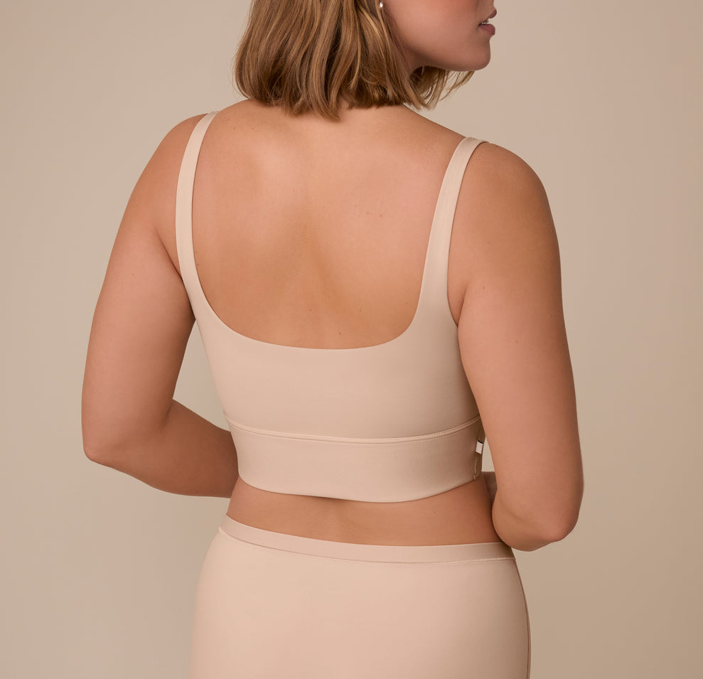 Sonnie turns to reveal the wide, scoop-back detail of the Bliss Square Neck Bralette in Beige, highlighting the seamless design and wireless support.