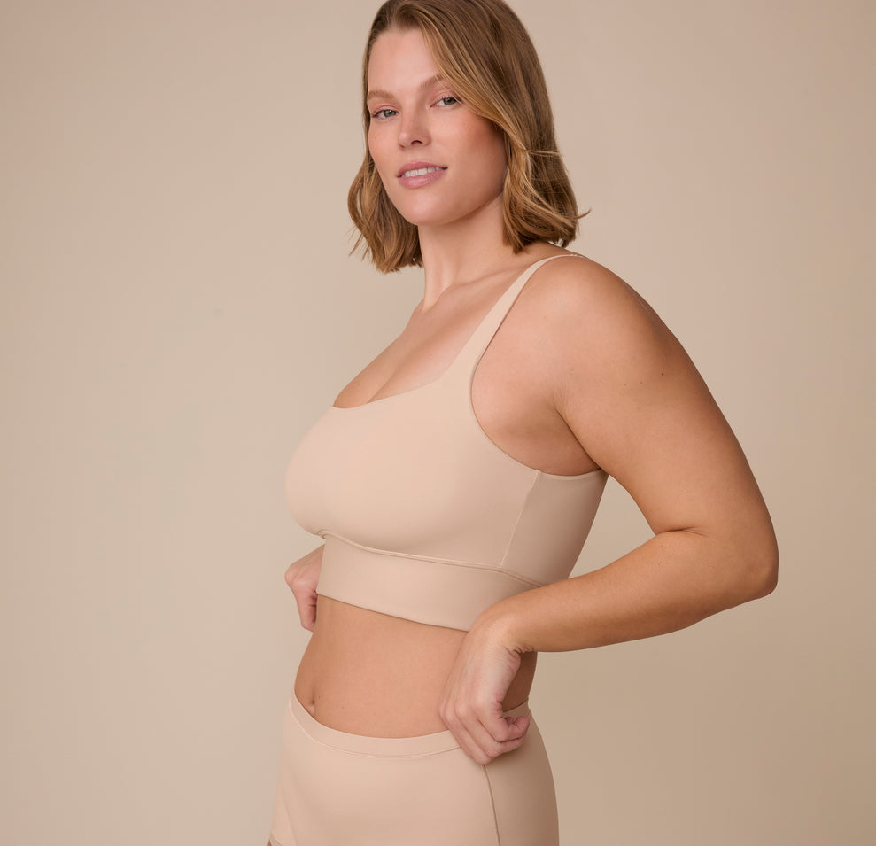 Sonnie stands at an angle, smiling slightly while showcasing the Bliss Square Neck Bralette's smooth, supportive fit with its longline band and squared-off neckline.