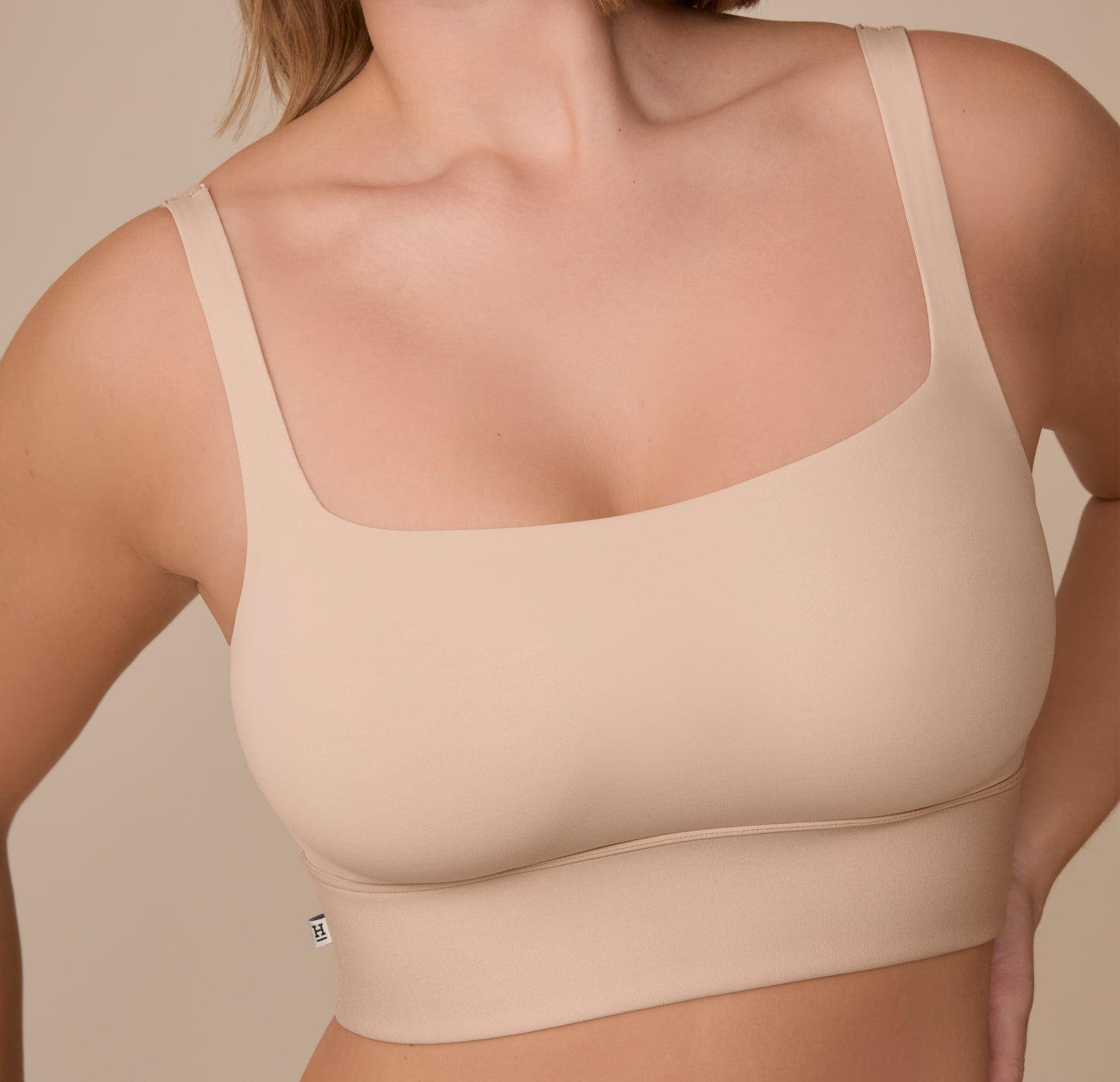 A tight shot of the Bliss Square Neck Bralette in Beige on Sonnie, focusing on the soft, buttery fabric, square neckline, and the small Harper Wilde tag along the outside band.