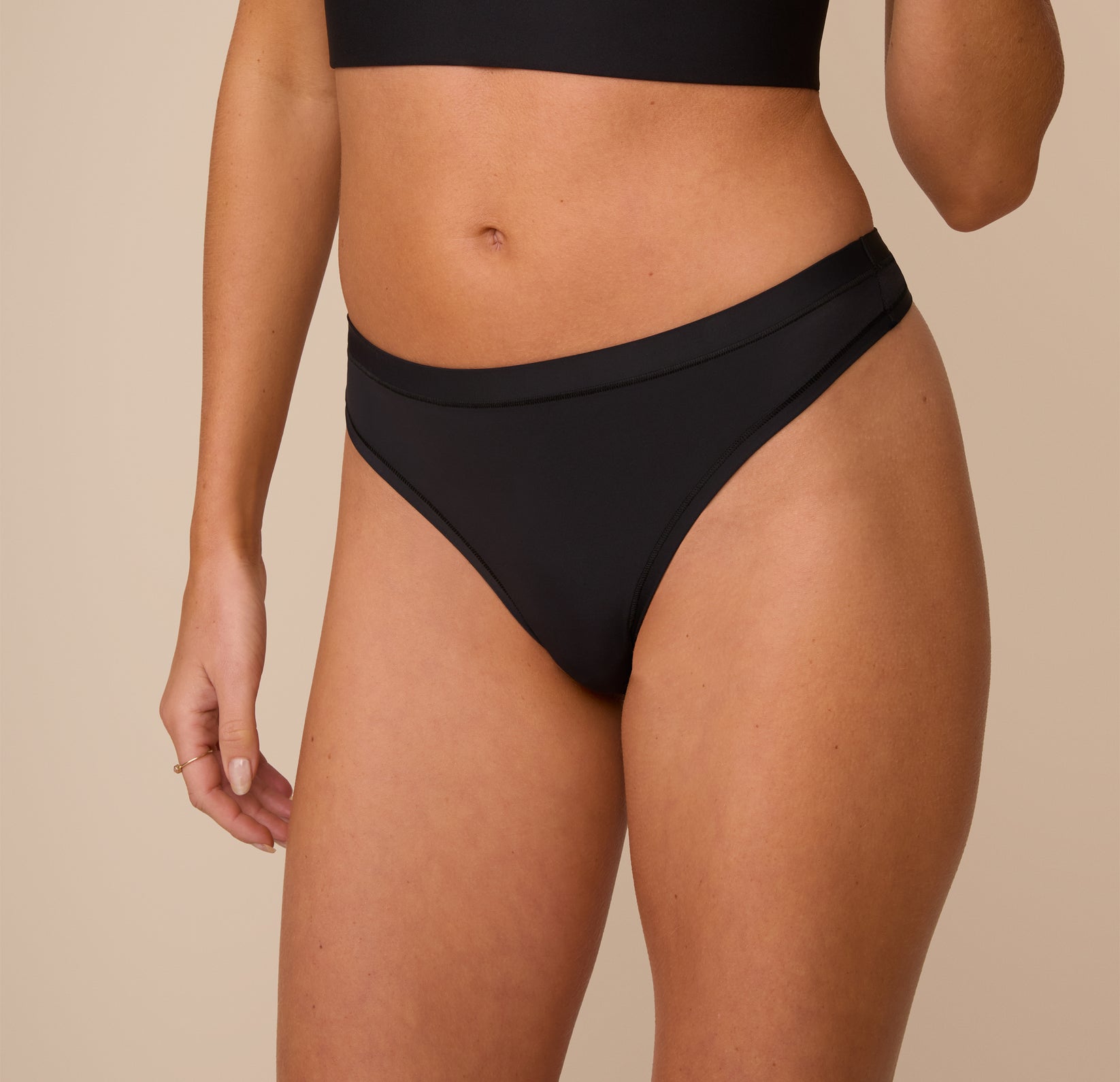 A close-up of Freya wearing the Bliss Thong in Black, emphasizing the smooth fabric, soft waistband, and stretchy construction for all-day comfort.