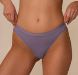 Close-up of the Bliss Thong in Eclipse worn by Marcela, focusing on the waistband detail and seamless side construction for a no-show fit beneath clothing.