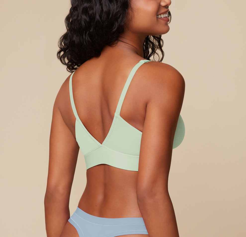 Back view of Ally in the Bliss Triangle Bralette in Dew, highlighting the deep V-back and supportive elastic band that provides a light, comfortable lift.