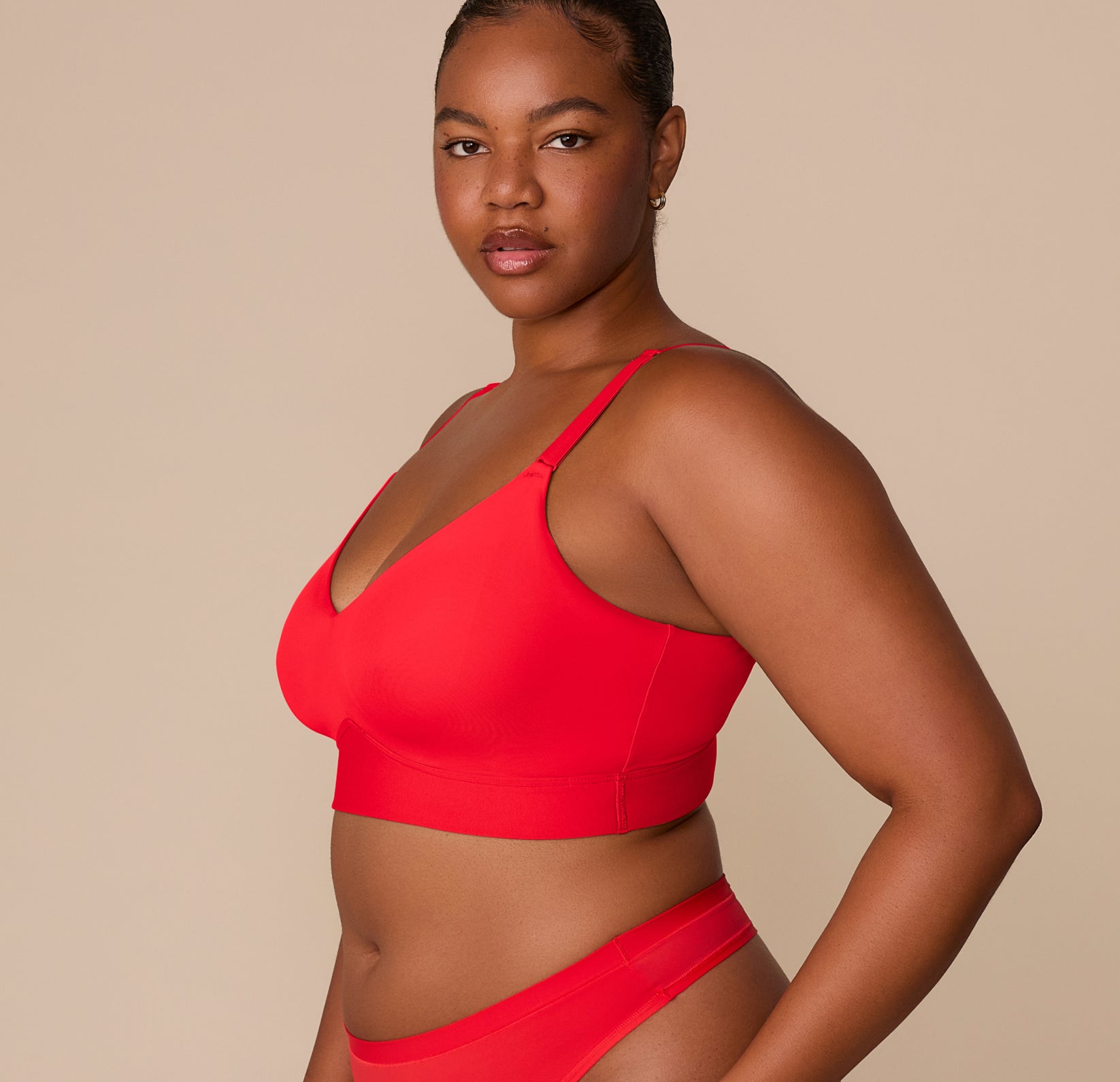 Side view of Zarria wearing the Bliss Triangle Bralette in Cherry. The image shows the curved underbust band and microfiber construction that provides supportive lift without wires.