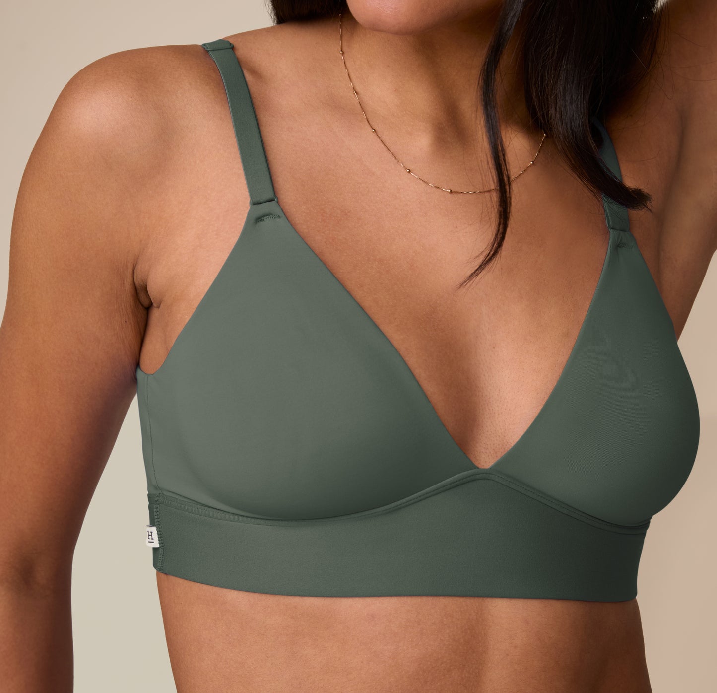Close-up detail of Nemesis in the Bliss Triangle Bralette in Fir, showing soft stretch fabric and minimalist logo tag.