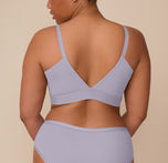 Zarria turns her back to the camera, displaying the deep V-back of the Bliss Triangle Bralette and the Bliss Hiphugger’s full coverage rear in Violet. The wide underband and smooth straps offer a comfortable and supportive fit.