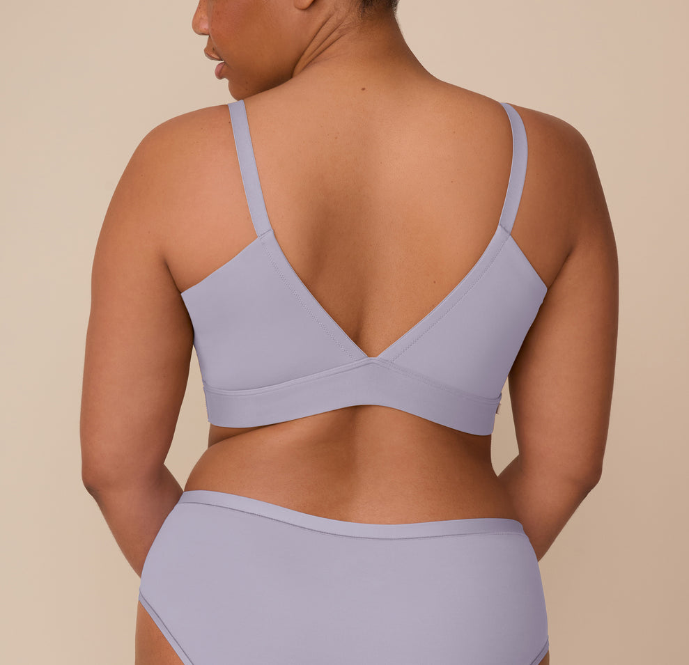 Zarria turns her back to the camera, displaying the deep V-back of the Bliss Triangle Bralette and the Bliss Hiphugger’s full coverage rear in Violet. The wide underband and smooth straps offer a comfortable and supportive fit.