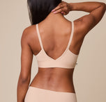 Ally turns to display the back of the Bliss Triangle Bralette in Beige, highlighting the smooth, stretchy fabric for a barely-there feel.