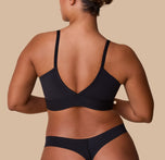 A back view of India wearing the Bliss Triangle Bralette in Black, showcasing the low-cut V-back and micro-fiber material.