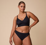India models the Bliss Triangle Bralette in Black with the matching Bliss Bikini, showcasing the smooth, seamless fit of the set.