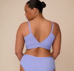 Back view of Zarria wearing the Bliss Triangle Bralette in Dusk. Her pose highlights the supportive V-back and smooth stretch fabric across the upper back and shoulders.