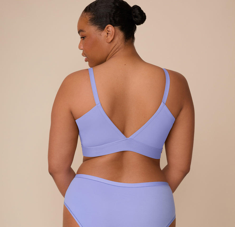 Back view of Zarria wearing the Bliss Triangle Bralette in Dusk. Her pose highlights the supportive V-back and smooth stretch fabric across the upper back and shoulders.