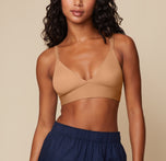 Ally poses at a front facing angle wearing the Bliss Triangle Bralette in Tan. The low cut V-neck and wide band are emphasized. sizing: Ally wears size XS