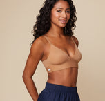 Ally poses at a three quarter angle wearing the Bliss Triangle Bralette in Tan. The sleek, seamless fabric and flattering triangular cup shape are emphasized.