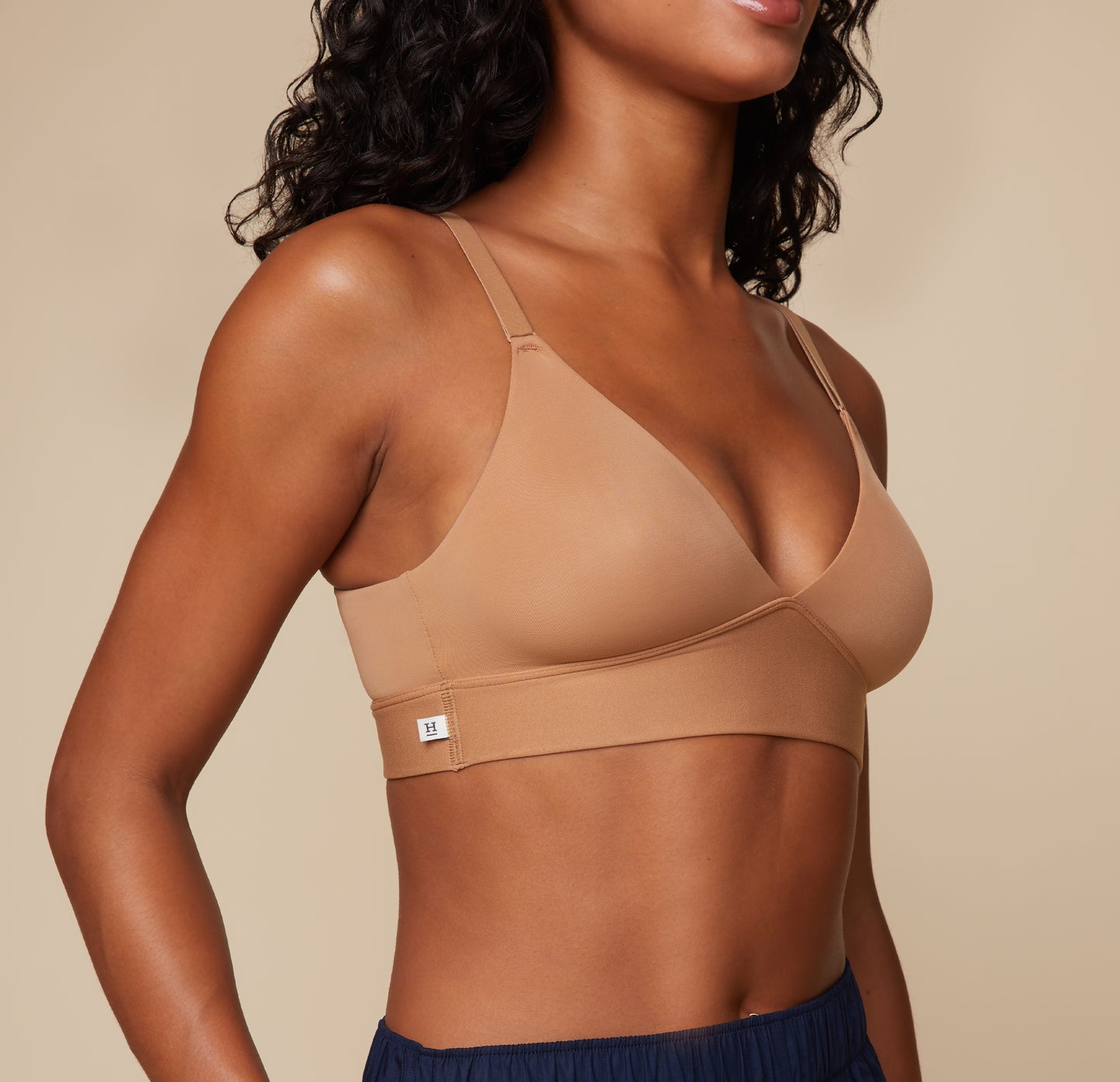 An up close shot of Ally wearing the liss Triangle Bralette in Tan. The small Harper Wilde tag on the outside of the band is emphasized for its convenient and comfortable placement.