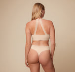 Back view of Megan wearing the Bliss Lace Halterneck Bralette and matching Highwaist Lace Thong in Beige. The image emphasizes the bralette’s halterneck lace strap and the thong’s high-waist design.
