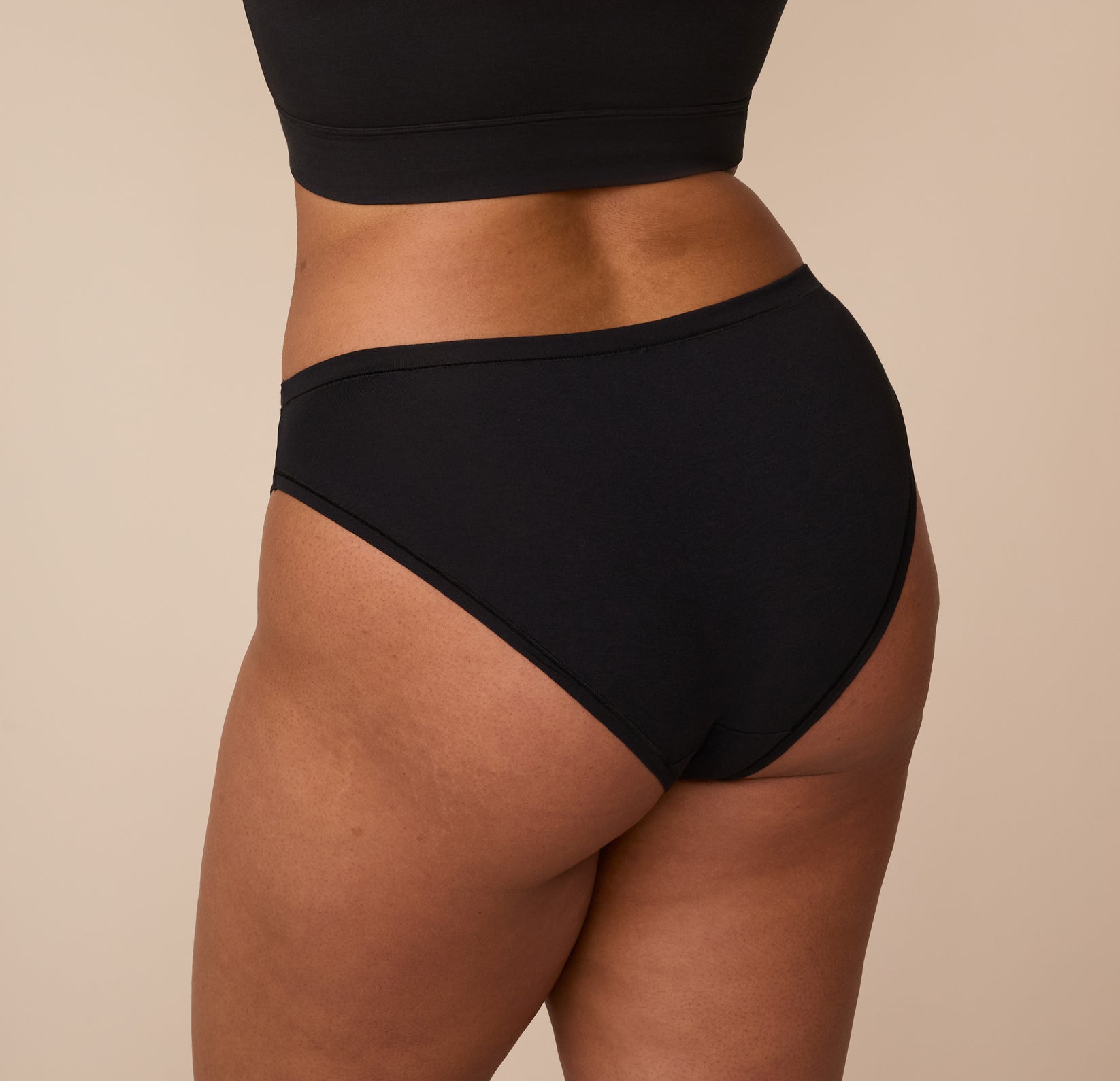 Rear view of Zarria in the Cloud Cotton Bikini in Black. The image shows the full-coverage back fit and gentle curve of the waistband for a secure, comfy feel.