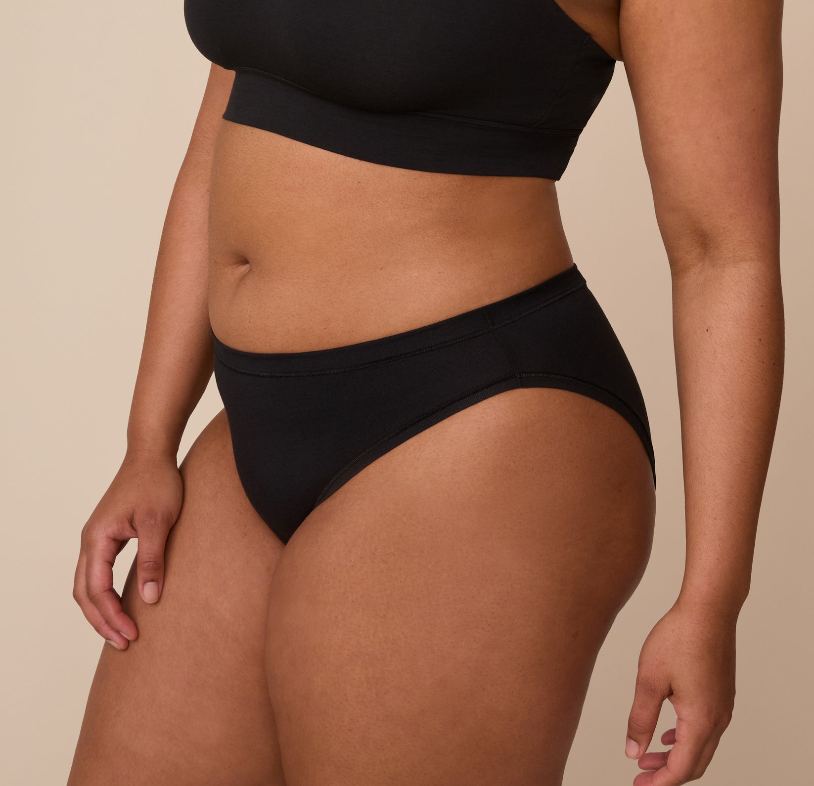 Three quarter angle of Zarria modeling the Cloud Cotton Bikini in Black. The image emphasizes the clean seam design and soft stretch along the hip.