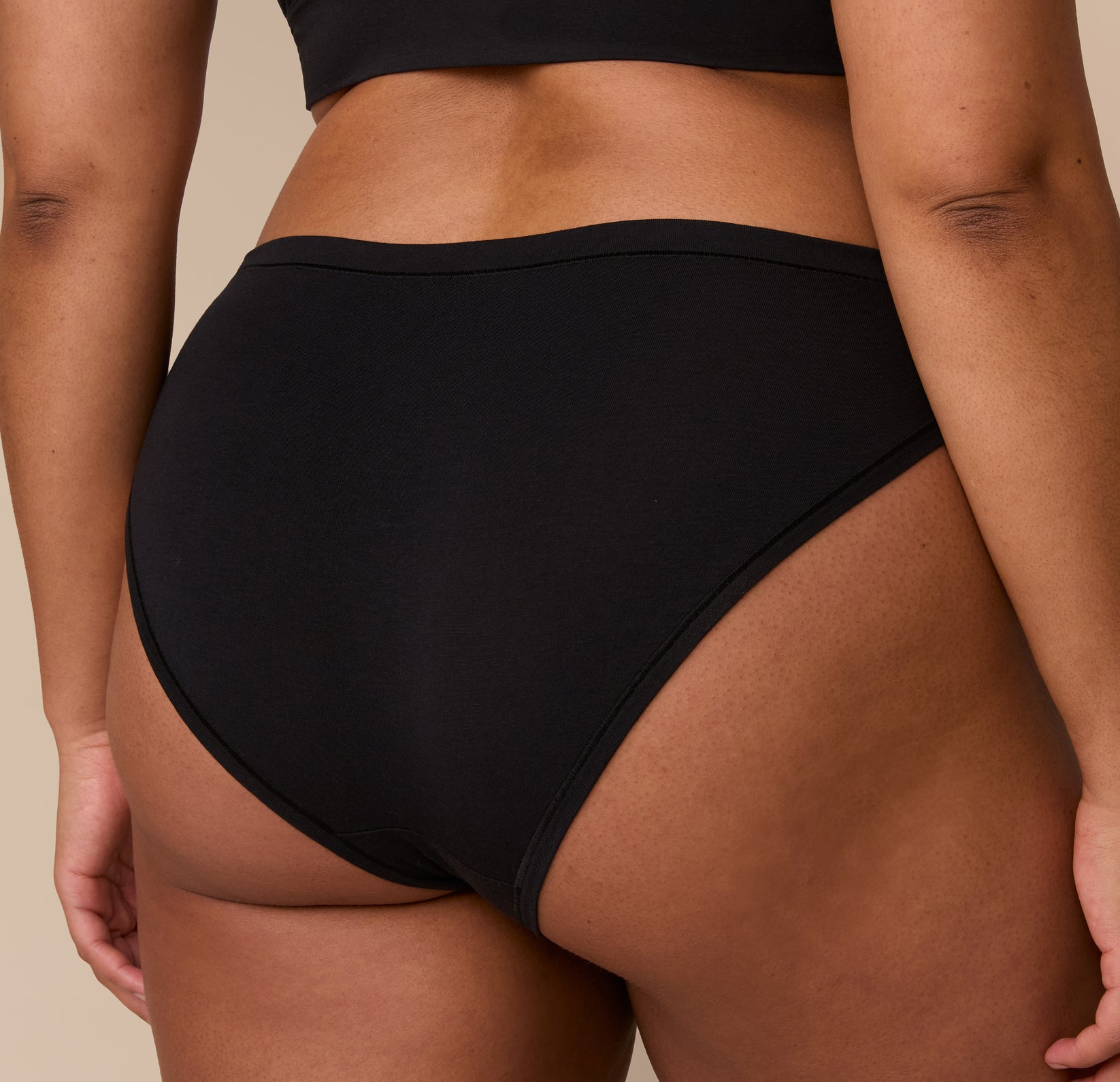 Back three-quarter view of Zarria in the Cloud Cotton Bikini in Black, focusing on the coverage and flattering cut at the leg openings.