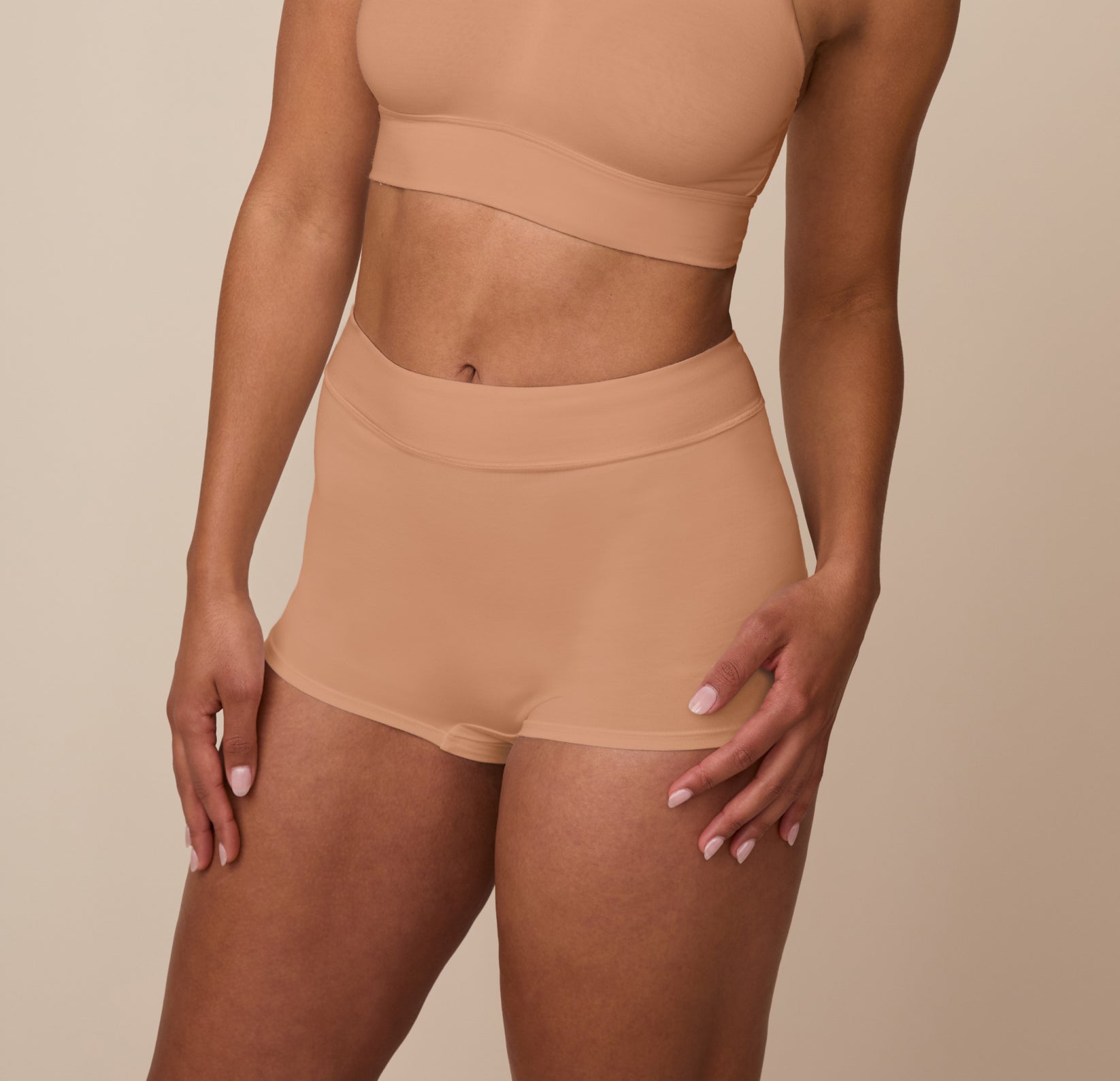 Angled front view of Nemesis wearing the Cloud Cotton High Waist Boyshort in Dune. The fit contours to the hips, emphasizing comfort and ease of movement.