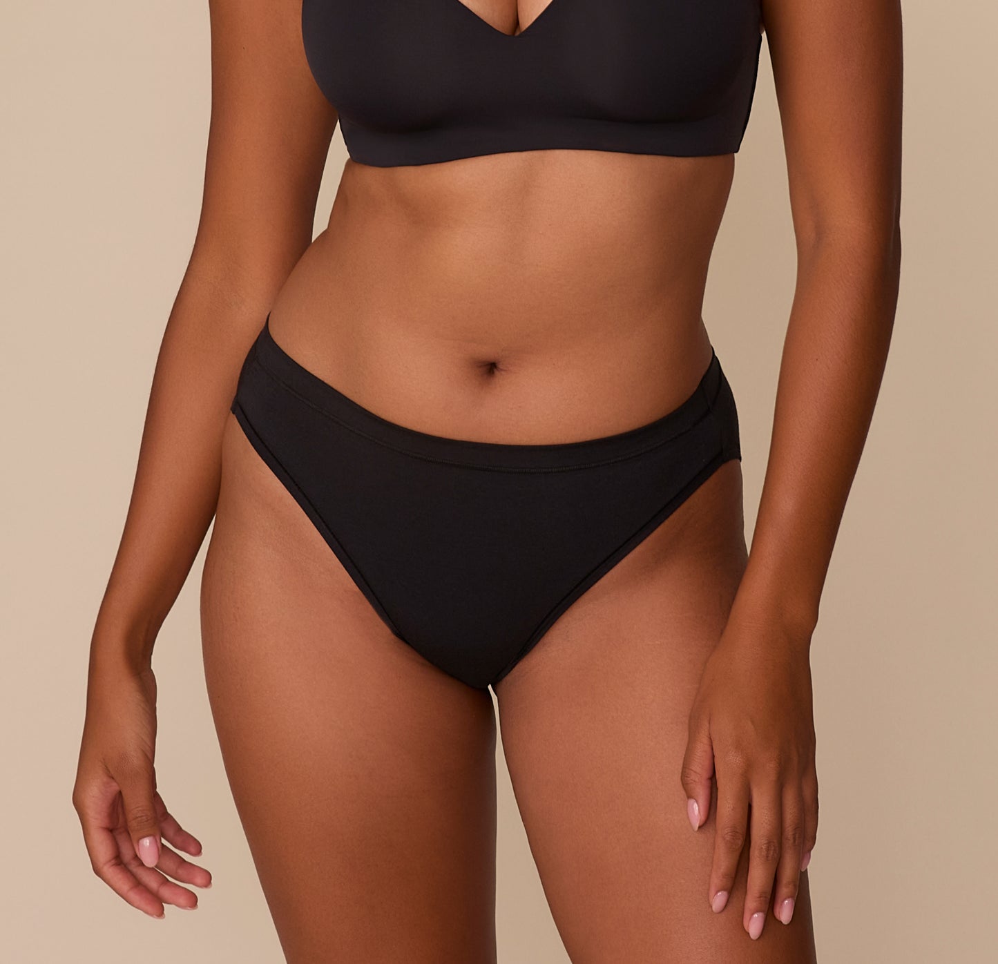 Victoria wears the Cloud Cotton French Cut Brief in Black, showcasing its mid-rise waistband and high-cut leg opening that elongates the legs and offers modern, breathable coverage. sizing: Victoria wears size Medium