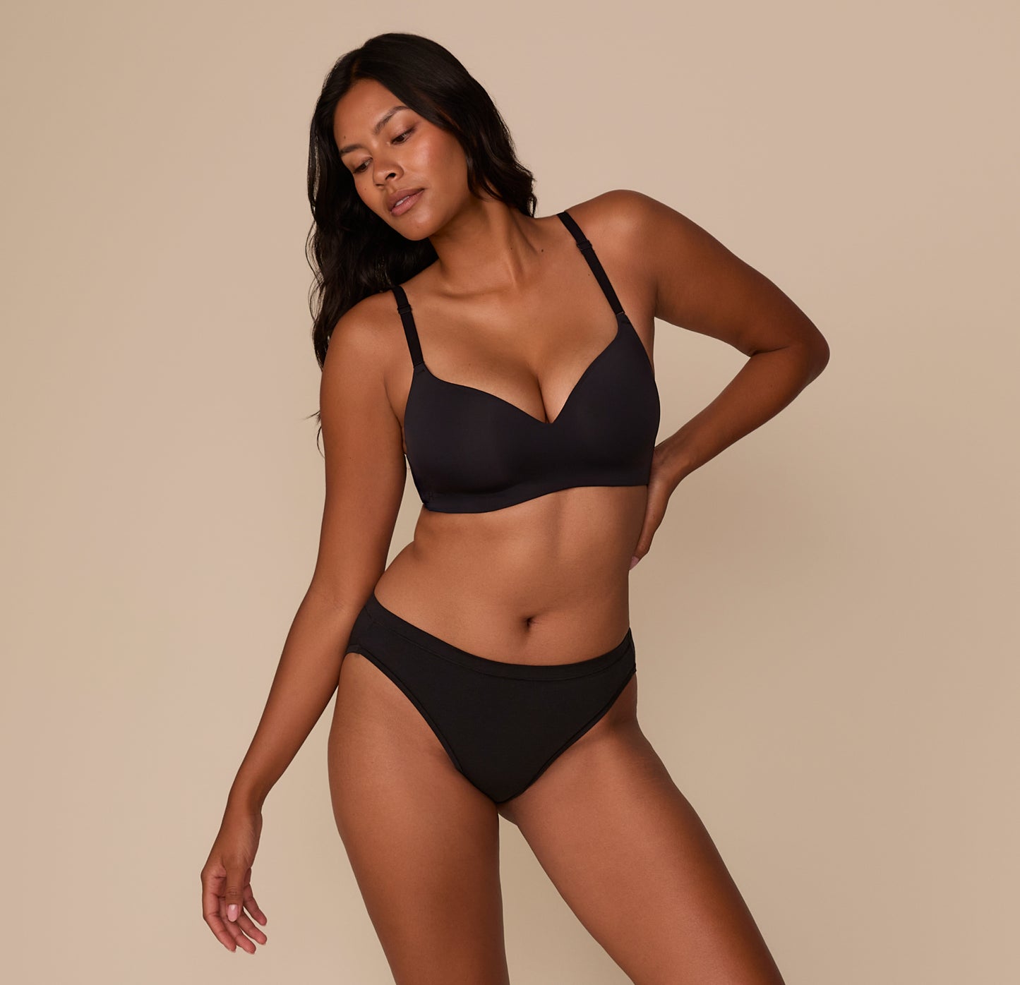Victoria poses in a full-body shot wearing the Cloud Cotton French Cut Brief and matching Base Wirefree T-Shirt Bra in Black, illustrating the flattering, smooth silhouette the set creates under clothing.