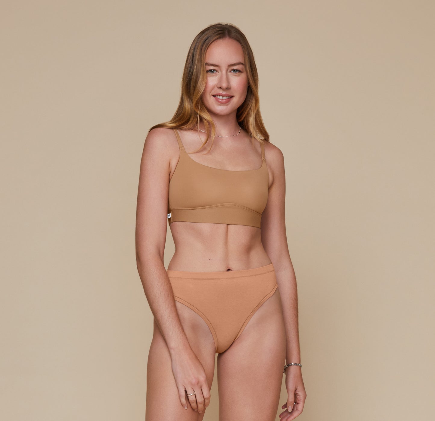 Front, full body view of Erin wearing the Bliss Scoop Bralette in the color Tan and the Cloud Cotton French Cut Brief in the color Dune.