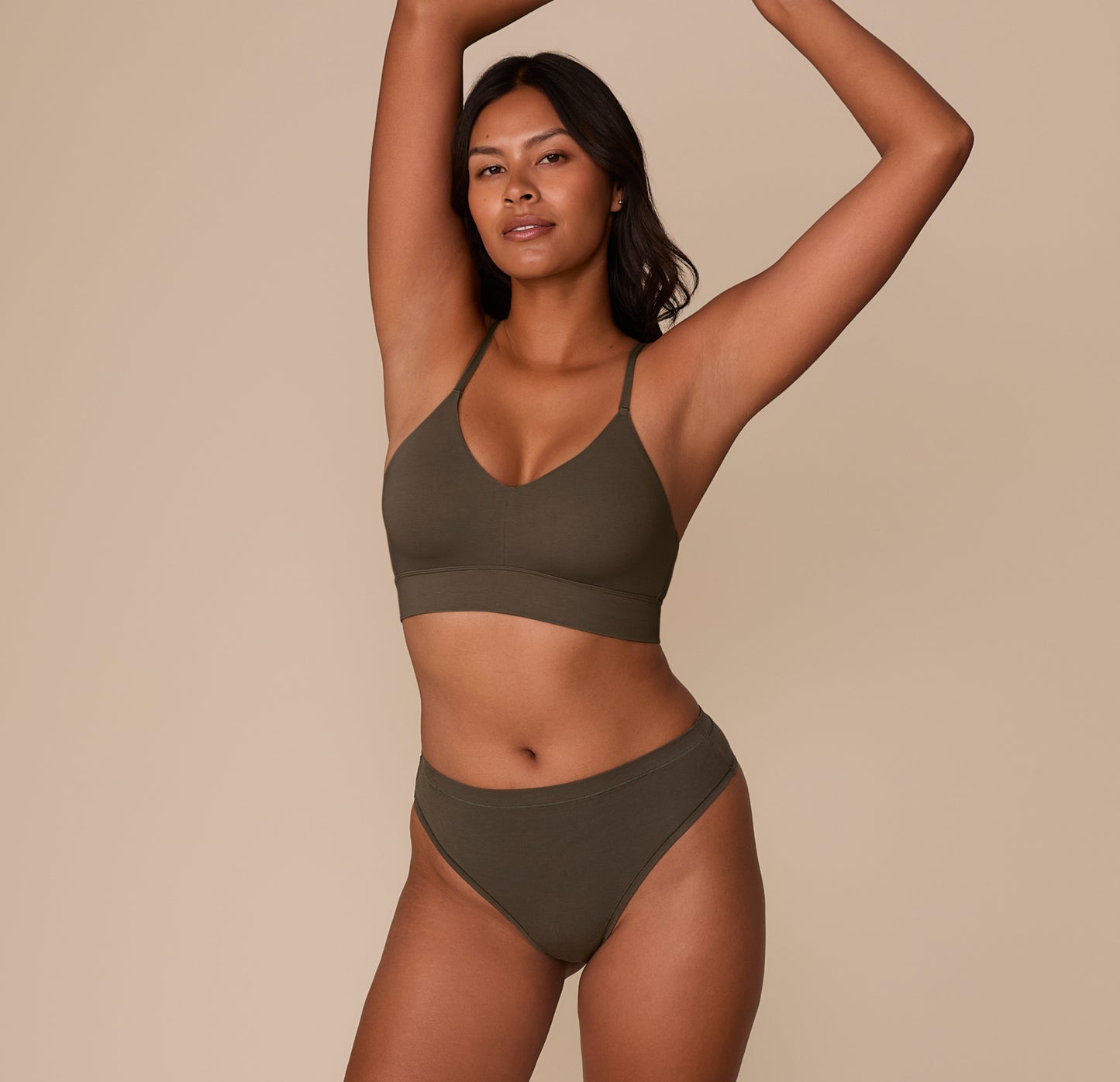 Victoria wearing the Cloud Cotton Highwaist Thong in Olive with the matching Triangle Bralette, standing with arms raised.