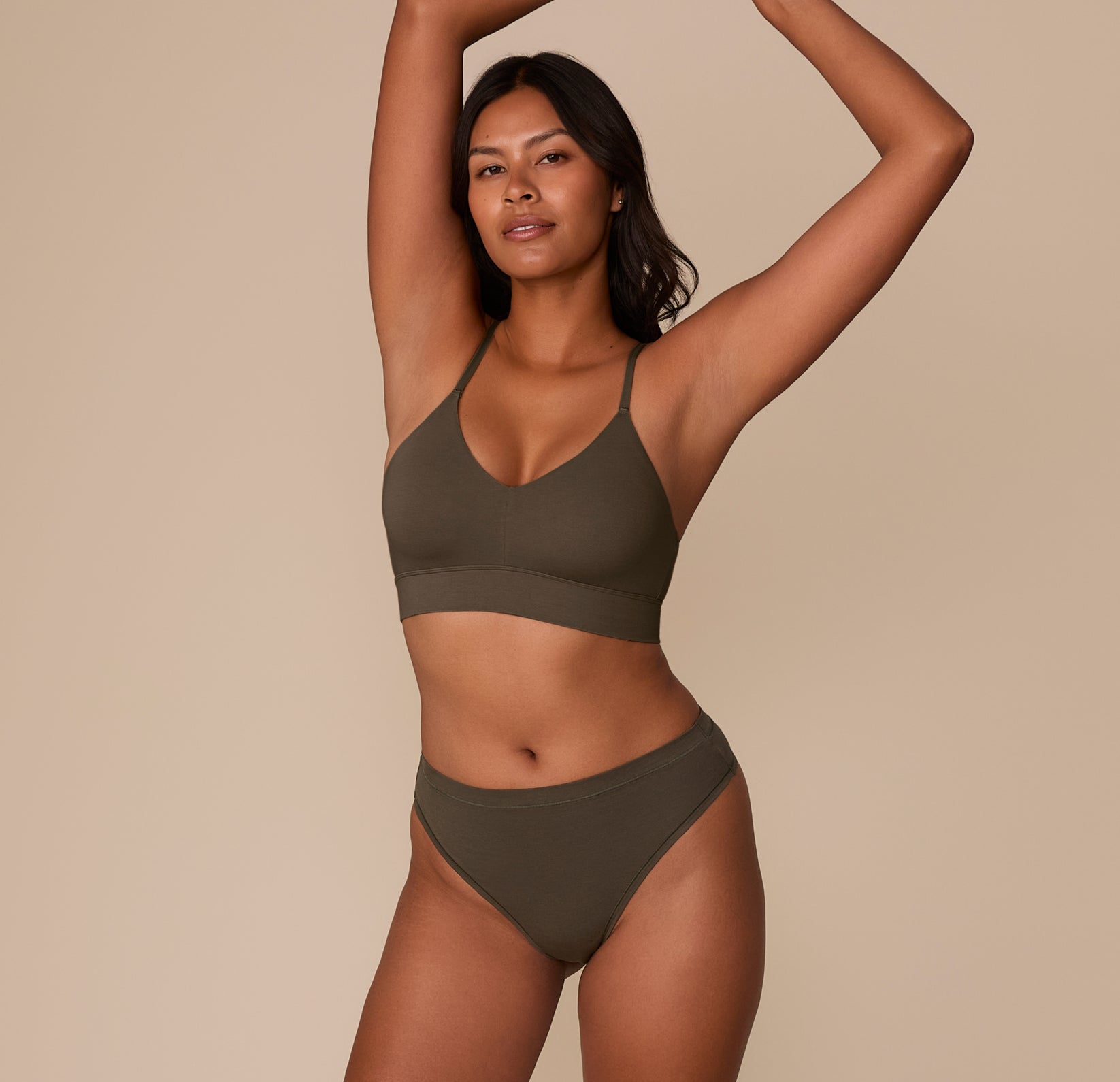 Victoria wearing the Cloud Cotton Highwaist Thong in Olive with the matching Triangle Bralette, standing with arms raised.