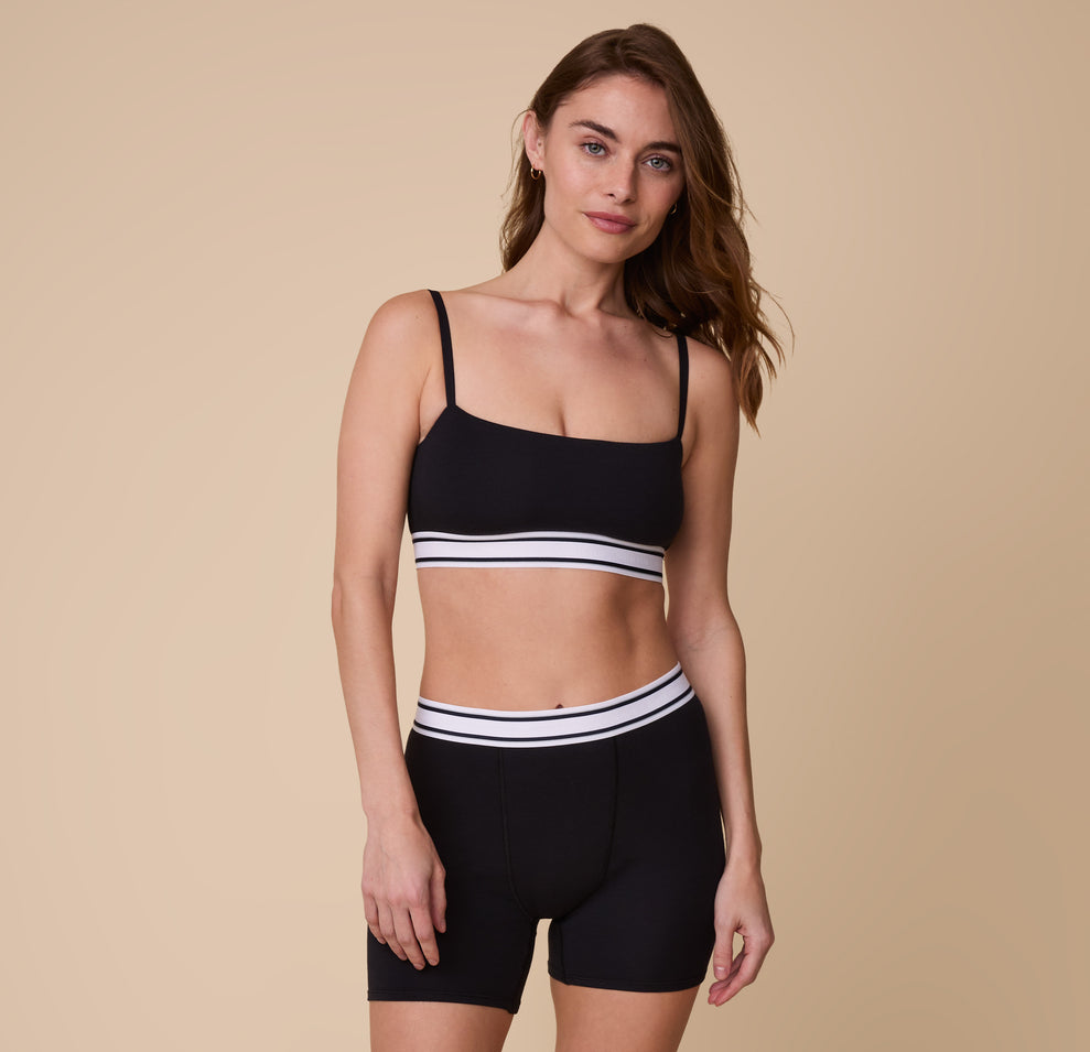 A full-length image of Gracie wearing the Cloud Cotton Retro Bandeau Bralette in Black, paired with the matching Cloud Cotton Boxer Brief in Black.