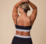 The back view of India modeling the Cloud Cotton Retro Bandeau Bralette in Black, with arms raised to highlight the adjustable straps and comfortable stretch fit.