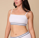 A close-up of Emersyn wearing the Cloud Cotton Retro Bandeau Bralette in White. The straight neckline and thin adjustable straps offer a sleek and minimal look, while the striped elastic underband adds a sporty touch. sizing: Emersyn wears size Large