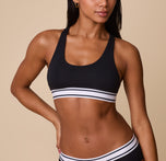 A close-up of Ally wearing the Cloud Cotton Retro Racerback Bralette in Black. The scoop neckline and striped elastic underband add a sporty and modern touch. sizing: Ally wears size Small