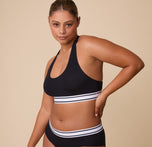 India is featured wearing the Cloud Cotton Retro Racerback Bralette in Black, styled with the matching Cloud Cotton Hiphugger. The bold contrast of black fabric with the striped underband makes for a sleek, classic look. sizing: India wears size Large