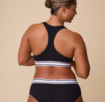 India showcases the full racerback cut of the Cloud Cotton Retro Racerback Bralette from behind, emphasizing the supportive and flattering fit.