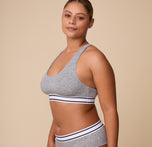 A relaxed three quarter profile of India in the Cloud Cotton Retro Racerback Bralette in Heather Charcoal, showcasing the smooth cotton fabric and contoured fit.